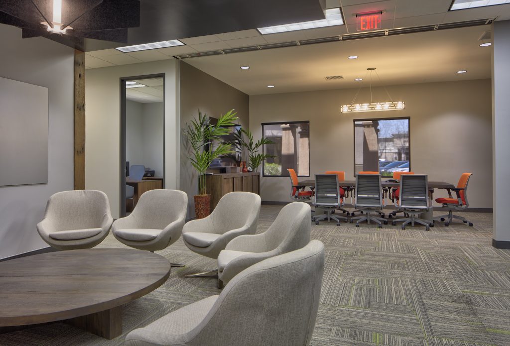 A coworking area with gray chairs in a circle. Behind the chairs, you can see a conference room.